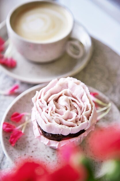 一杯のコーヒーと美的なピンクのカップケーキ 花の装飾 休日の食べ物のお祝いの背景