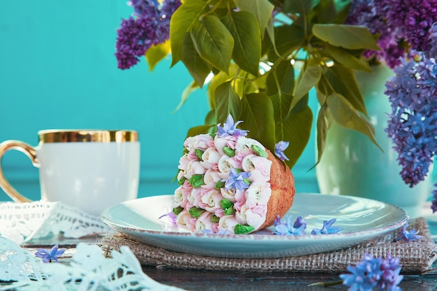 Cupcake floreale rosa estetico con fiori lilla con tazza da caffè piatta all'aperto all'ombra