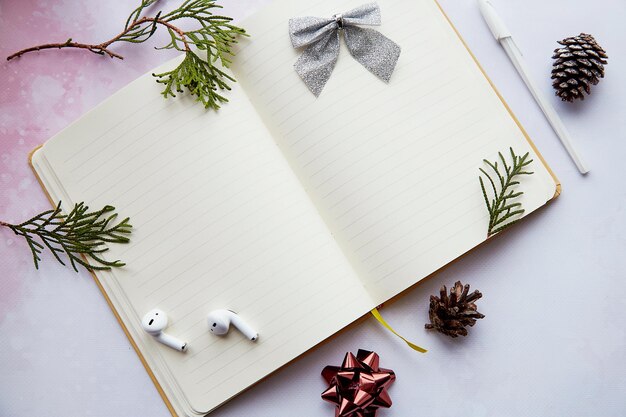 Aesthetics mock up notepad with decorations wireless earphones in home office New year resolution new start and list of goals concept