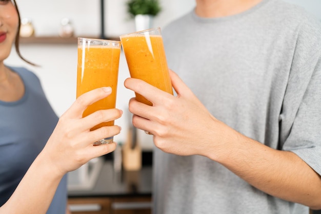 Afbeelding bijsnijden van een gelukkig Aziatisch stel geniet van het drinken van gezonde veganistische smoothie op het aanrecht Paar dat samen thuis veganistische smoothie maakt voor een gezonde levensstijl