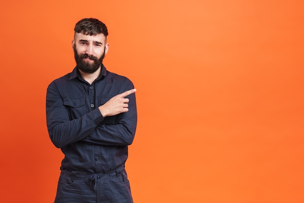 Afbeelding close-up van brunette man met neus sieraden dragen zwart shirt wijzende vinger opzij naar copyspace