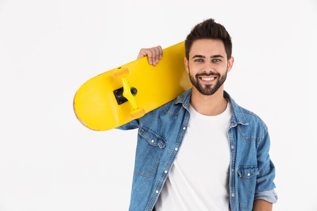 Afbeelding close-up van ongeschoren tevreden man glimlachend en staande met skateboard geïsoleerd over witte muur