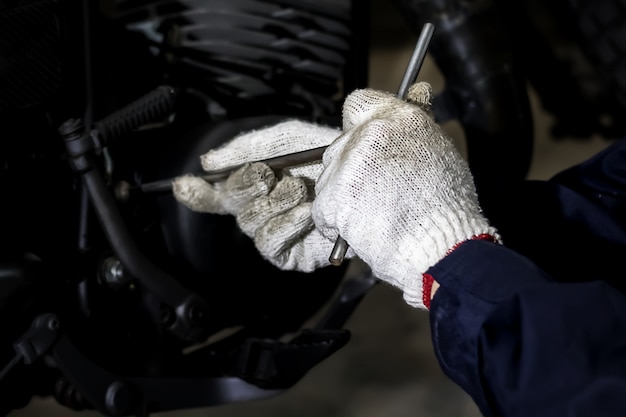 Afbeelding is close-up, mensen repareren een motorfiets Gebruik een sleutel en een schroevendraaier om te werken.