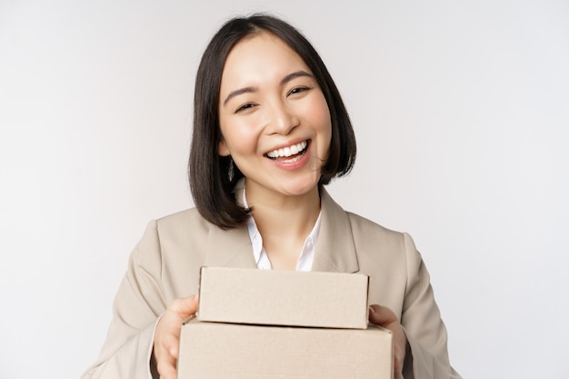 Afbeelding van Aziatische verkoopster zakenvrouw die dozen geeft met bestelling leveren aan klant die in pak staat op witte achtergrond