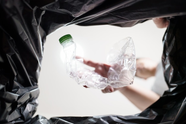 Afbeelding van de binnenkant van de gele recyclingzak van de mens die lege plastic fles in de prullenbak gooit Home recycle eco green zero concept