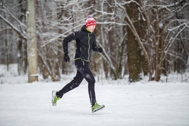 Afbeelding van de zijkant van de man met een rode sportmuts op een run in de winter