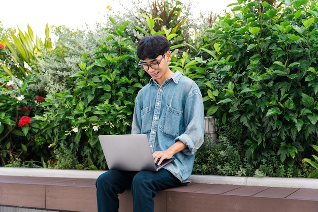 Afbeelding van een aziatische jongen die zit en een computer gebruikt op de schoolcampus