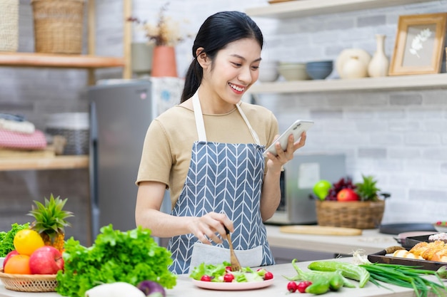 Afbeelding van een Aziatische vrouw die salade in de keuken bereidt