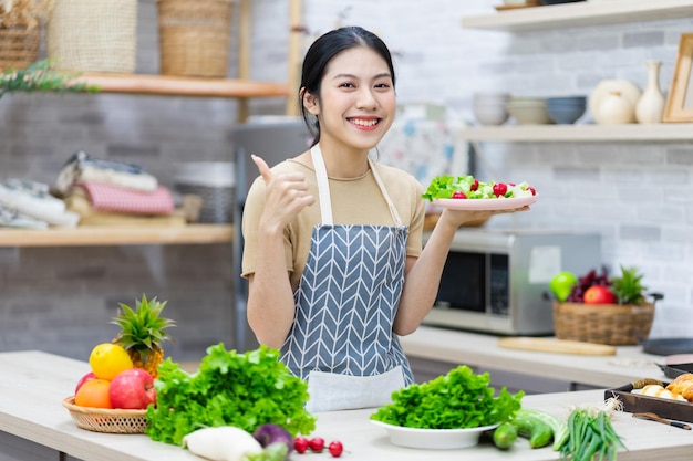 Afbeelding van een Aziatische vrouw die salade in de keuken bereidt