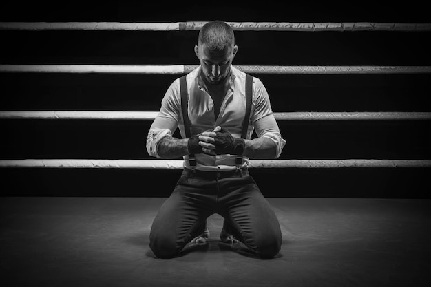 Afbeelding van een brutale man geknield in de ring. Hij bidt voor het gevecht. Het concept van vuistgevechten. Gemengde media