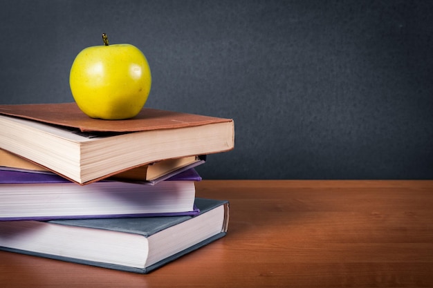 Afbeelding van een bureau met een stapel schoolboeken en appel