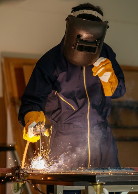 Afbeelding van een gelaste stalen plaat lassen in een industriële fabriek. Hij draagt volledige beschermingsmiddelen zoals maskers, handschoenen, laspakken. Dit soort werk vereist specifieke vaardigheden.