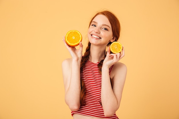 Afbeelding van een gelukkige jonge mooie roodharige vrouw poseren geïsoleerd over gele muur met oranje.