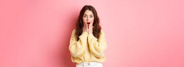Foto afbeelding van een geschokte en verraste brunette vrouw die naar adem snakkend naar groot nieuws kijkt met open mond hand in hand