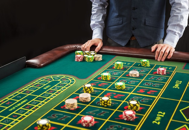 Afbeelding van een groene tafel en wedden met chips. Man overhandigen casinofiches op roulettetafel. Detailopname