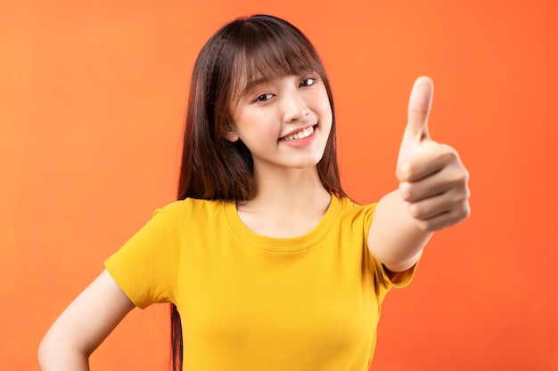 Afbeelding van een jong Aziatisch meisje met gele t-shirt op oranje