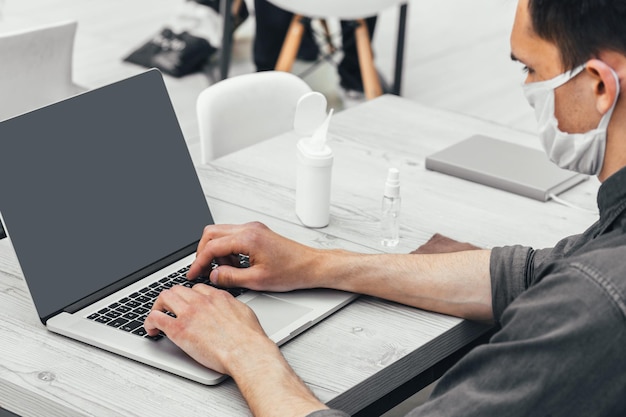 Afbeelding van een jonge man aan het werk op een laptop op een openbare plaats