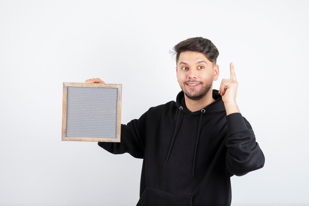 Afbeelding van een jonge man in zwarte hoodie met leeg frame