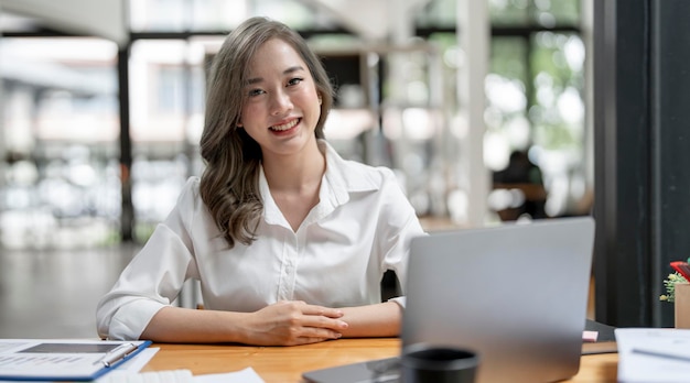 Afbeelding van een jonge, mooie, vrolijke vrouw die lacht terwijl ze met een laptop op kantoor werkt