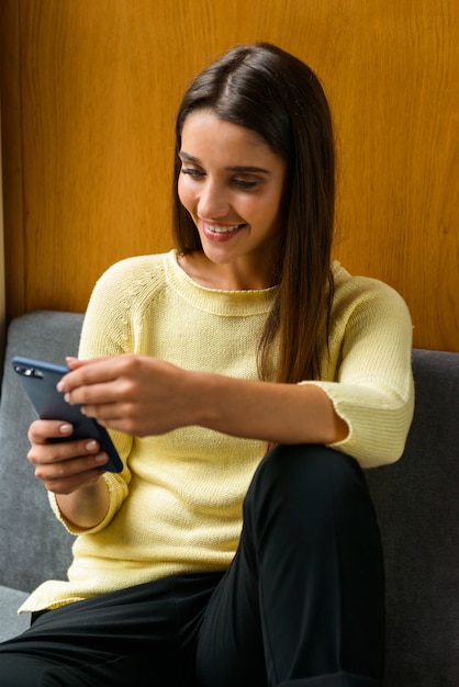 Afbeelding van een jonge student geconcentreerde vrouw in bibliotheek met behulp van mobiele telefoon.