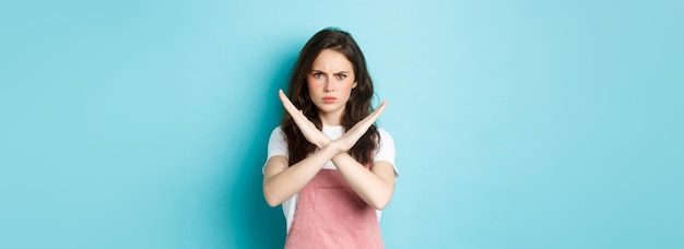 Foto afbeelding van een jonge teleurgestelde vrouw die fronsend een kruisteken maakt en mokkend laat zien dat een stopgebaar nee zegt