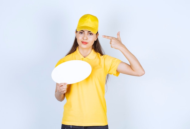 Afbeelding van een jonge vrouw in geel uniform poseren met lege tekstballon.