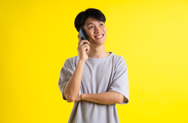 Afbeelding van een knappe jonge man die zijn telefoon gebruikt en poseert op een gele achtergrond