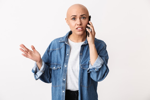 Afbeelding van een mooie ontevreden boze kale vrouw poseren geïsoleerd, praten via de mobiele telefoon.