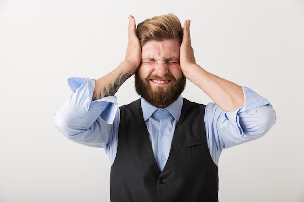 Afbeelding van een nerveuze ontevreden jonge bebaarde man die geïsoleerd over witte muur.