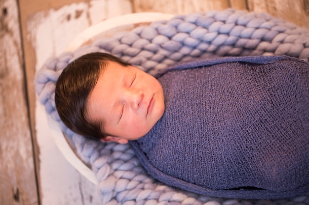 afbeelding van een pasgeboren Braziliaanse baby gekruld slapen in een deken