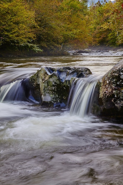 Afbeelding van een portretopname van een ondiepe waterval die over rotsblokken stroomt