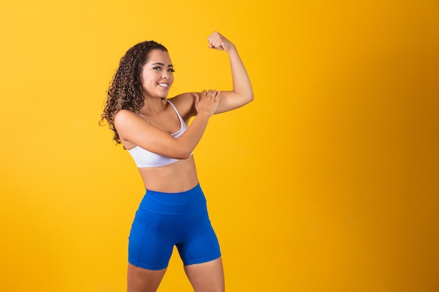 Afbeelding van een sterk, zelfverzekerd Afro-Amerikaans meisje dat haar biceps buigt en naar hem wijst.