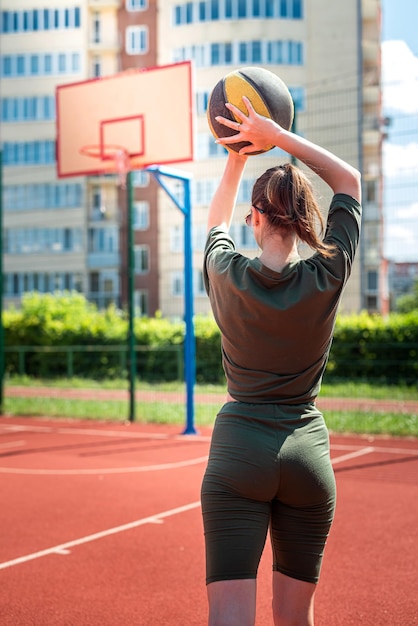 Afbeelding van een sterke jonge, sportieve fitnessvrouw-basketbalspeler die een basketbal vasthoudt voor het spel