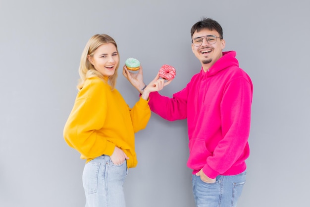 Afbeelding van een tevreden stel man en vrouw die lacht terwijl ze samen zoete donuts eten