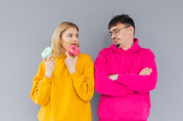 Afbeelding van een tevreden stel man en vrouw die lacht terwijl ze samen zoete donuts eten