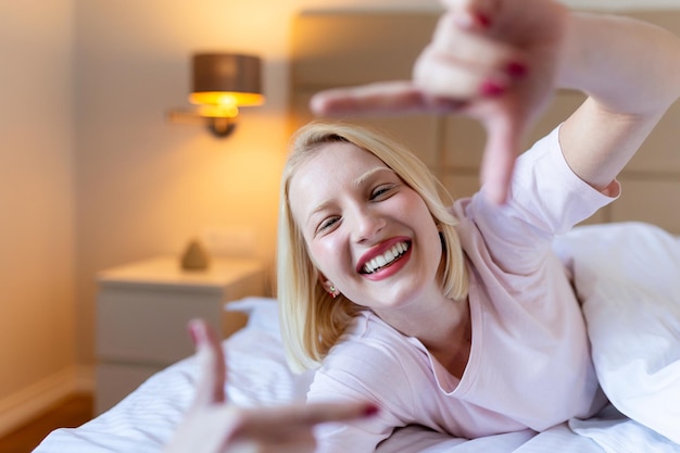 Afbeelding van een vrouw die een fotolijstje met de vingers maakt terwijl ze in bed ligt