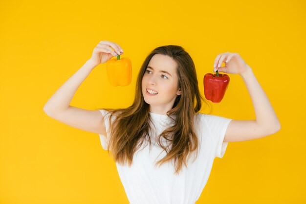 Afbeelding van emotionele positieve jonge mooie vrouw die paprika's vasthoudt en poseert