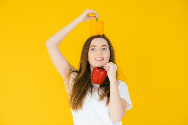 Afbeelding van emotionele positieve jonge mooie vrouw die paprika's vasthoudt en poseert