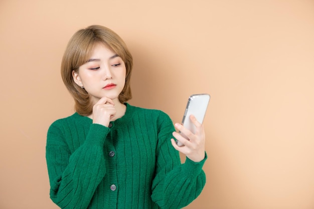 Afbeelding van ernstige mooie vrouw typen op mobiele telefoon geïsoleerd over beige achtergrond