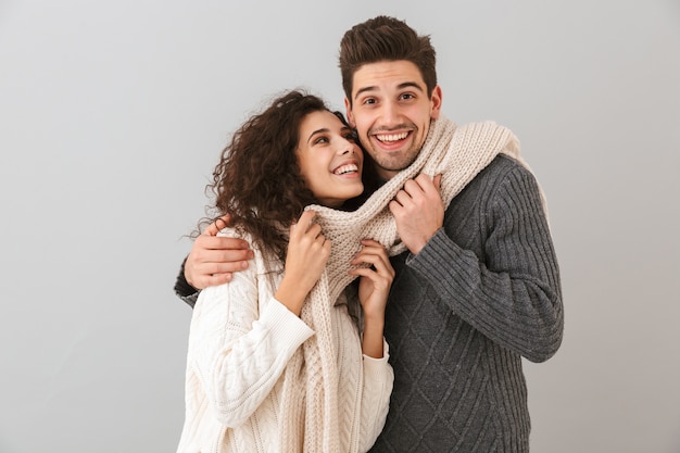 Afbeelding van gelukkige paar man en vrouw lachend terwijl samen knuffelen, geïsoleerd over grijze muur