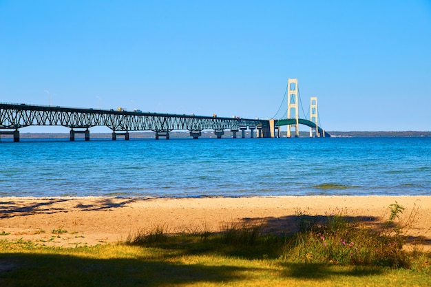 Afbeelding van gigantische hangbrug over Lake Michigan met woelige golven en een zandstrand