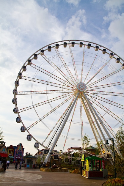 Afbeelding van Groot reuzenrad in het midden van een kermis tegen een gedeeltelijk bewolkte hemel