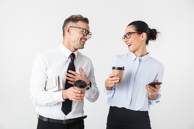 Afbeelding van jonge collega's paar geïsoleerd over witte muur koffie drinken met behulp van mobiele telefoons.