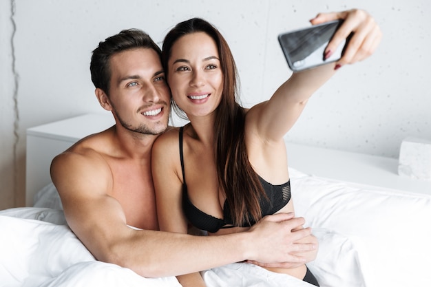 Afbeelding van Kaukasische paar man en vrouw samen selfie foto, liggend in bed thuis of hotel appartement