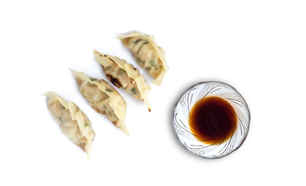 Afbeelding van knoedels of gyoza met sojasaus op wit wordt geïsoleerd