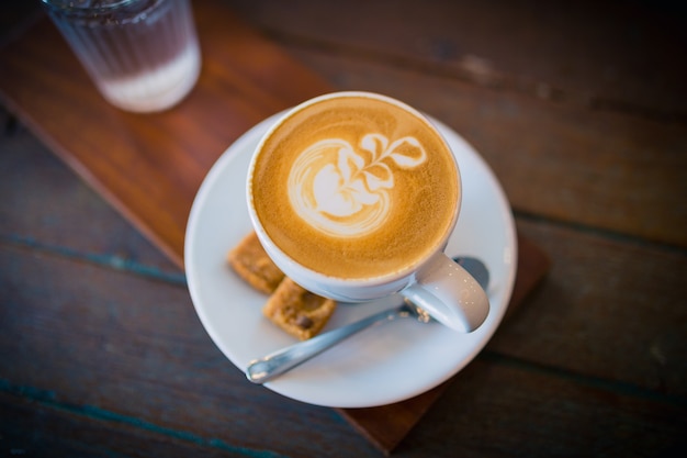 Afbeelding van latte warme koffie met schuimmelkkunst op een houten tafel