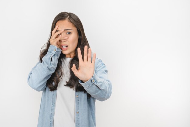 Afbeelding van mooie jonge bang vrouw die haar gezicht bedekt poseren geïsoleerd op witte achtergrond