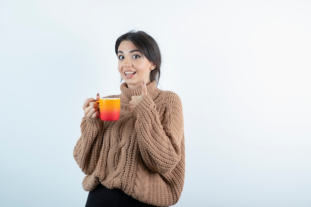 Afbeelding van mooie vrouw in gebreide met oranje kopje thee