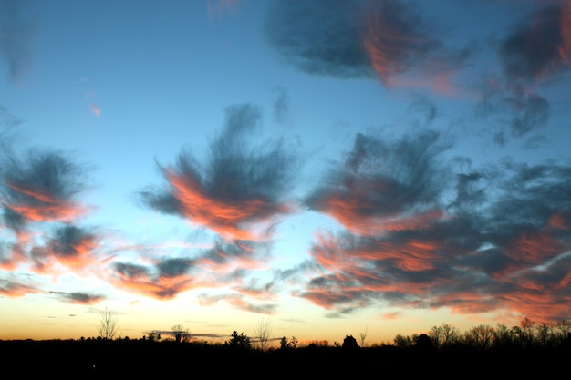 Afbeelding van piekerige wolken die de horizon bedekken en de kleuren van de zonsondergang weerspiegelen