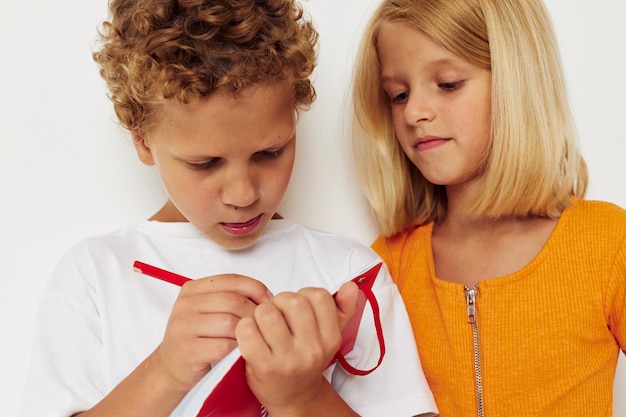 Foto afbeelding van positief jongens- en meisjesplezier in kleurrijke t-shirts met een notitieblok geïsoleerde achtergrond ongewijzigd